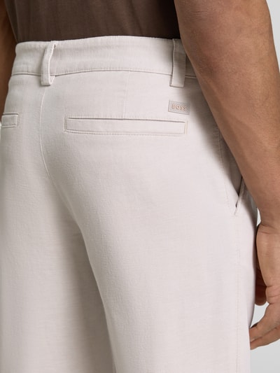 Männermodel trägt Tapered Fit Chino aus Baumwoll-Mix Modell 'CHINO PLEATED' von BOSS Orange, Optik: Unifarben, Detailaufnahme.