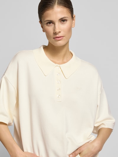 Frauenmodel trägt Oversized Strickpullover mit Polokragen Modell 'talla' von Gestuz, Viskose-Mix, kurze Knopfleiste, Label-Stitching, gerippte Abschlüsse, 3/4-Ärmel, cremefarben, glatte Textur, Nahaufnahme Oberkörper.