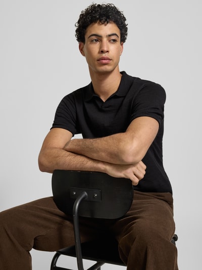 Männermodel trägt Slim Fit Poloshirt in Strick-Optik Modell 'Kane' von JACK & JONES, reine Baumwolle, Schwarz, Nahaufnahme Oberkörper.