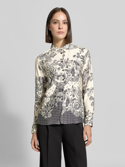 Frauenmodel trägt Regular Fit Hemdbluse aus reiner Viskose von Milano Italy mit floralen Mustern in Schwarz auf cremefarbenem Grund, ganzkörperansicht von vorne. Rückenlänge 58 cm, Ärmellänge 61 cm, Hemdblusenkragen, durchgehende Knopfleiste, langärmeliges Design.