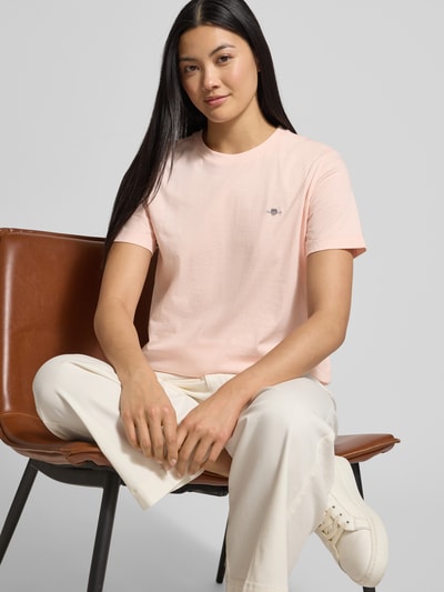 Frauenmodel trägt T-Shirt mit Label-Stitching und Rundhalsausschnitt von Gant, in zartem Rosa, Reine Baumwolle, Regular-Fit, Ganzkörperansicht von vorne. Rückenlänge bei Größe S: 57 cm.