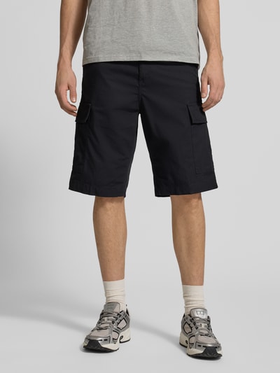 Mannenmodel draagt Shorts mit Cargotaschen van Carhartt Work In Progress in regular fit, cargozakken, achterzakken, zwart, volledige lichaamsvoorzijde.
