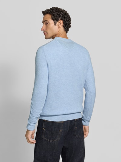 Männermodel trägt Slim Fit Strickpullover aus reiner Wolle mit Label-Stitching von MCNEAL in Hellblau, gerippte Abschlüsse, Ganzkörperansicht Rückansicht. Rückenlänge bei Größe M: 66 cm, Ärmellänge bei Größe M: 69 cm.