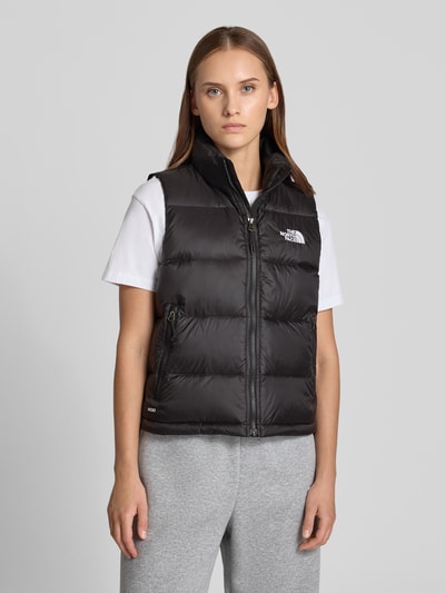 Frauenmodel trägt Steppweste mit Label-Stitching Modell 'HYDRENALITE DOWN A-LINE' von The North Face in Schwarz, glatte Textur, silberner Reißverschluss, Reißverschlusstaschen, Regular Fit, Stehkragen, Nahaufnahme Oberkörper.