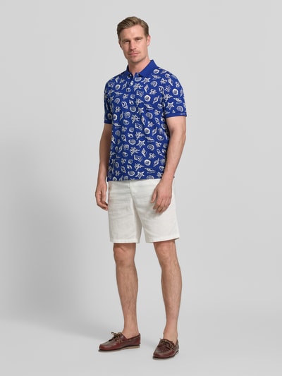 Männermodel trägt Regular Fit Poloshirt mit Allover-Motiv-Print von Gant in Blau aus Reine Baumwolle mit Polokragen, Kurzärmelig, Ganzkörperansicht von vorne. Rückenlänge bei Größe M: 68 cm.