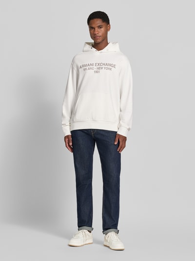 Männermodel trägt Hoodie mit Label-Print van Armani Exchange, puur katoen, los model, capuchon, kangoeroezak, elastische boordjes, Ganzkörperansicht von vorne.
