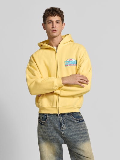 Męski model nosi Sweatjacke aus reiner Baumwolle od RHUDE w kolorze żółtym, relaxed fit, kaptur, dwukierunkowy zamek, kieszeń kangurka, szerokość w rozmiarze M: 64 cm, długość tyłu w rozmiarze M: 60 cm, długość rękawa w rozmiarze M: 54 cm, pełny widok z przodu