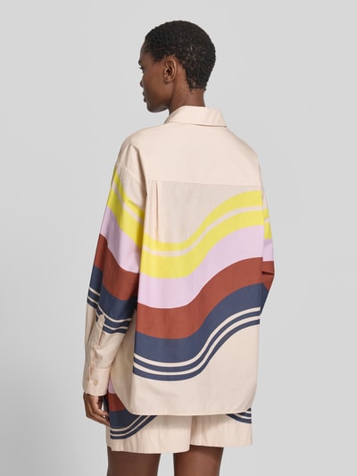 Frauenmodel trägt Boxy Fit Langarmbluse aus reiner Baumwolle Modell 'JOPPY' von Essentiel Antwerp, Beige mit bunten Streifen, Ganzkörperansicht Rückansicht.