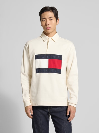 Männermodel trägt Regular Fit Sweatshirt aus reiner Baumwolle von Tommy Hilfiger, unifarben, langarm, Polokragen, Label Patch, Ganzkörperansicht von vorne.