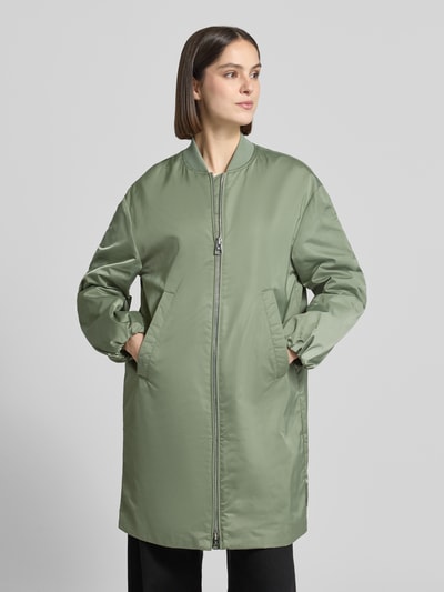 Modelka kobieca nosi Regular Fit Blouson-Mantel mit College-Kragen od Marc O'Polo, efekt: jednolity kolor, satyna, krój regular fit, kształt kołnierza: kołnierz college, zamek błyskawiczny dwustronny, naszywka z logo, długi rękaw z elastycznym zakończeniem, wpuszczane kieszenie boczne, kieszeń wewnętrzna, wykończenie materiału: satyna. Ganzkörperansicht z przodu.