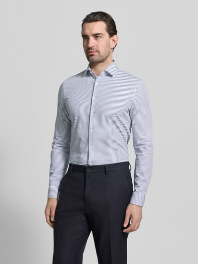 Męski model nosi Slim Fit Freizeithemd mit Kentkragen Modell 'Performance' od OLYMP No. Six, biało-granatowe paski, elastyczna bawełna, krój slim fit, perspektywa: ujęcie całej sylwetki z przodu.