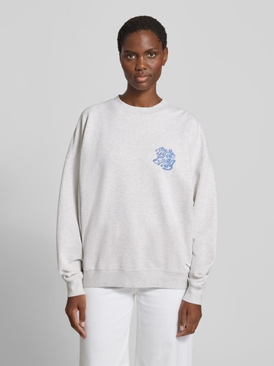 Frauenmodel trägt Relaxed Fit Sweatshirt mit Logo-Print von Anine Bing aus reiner Baumwolle, hellgrau mit blauer Logo-Print, elastische Abschlüsse, Rundhalsausschnitt, Rückenlänge bei Größe S 61 cm, Ganzkörperansicht von vorne.