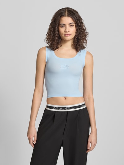 Frauenmodel trägt Slim Fit Top mit Logo-Detail von ANOTHER COTTON LAB in Hellblau, elastischer Baumwoll-Mix, Nahaufnahme Oberkörper.