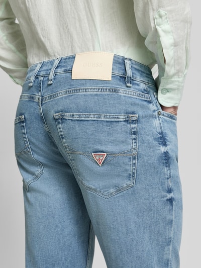 Männermodel trägt Straight Leg Jeans im 5-Pocket-Design Modell 'ANGELS' von Guess in hellblau, Detailaufnahme Rückansicht, Baumwoll-Mix mit Stretch-Anteil.