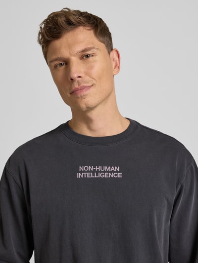 Männermodel trägt Sweatshirt mit Rundhalsausschnitt Modell 'Ryan' von Wood Wood in Dunkelgrau, Reine Baumwolle, Lockere-Schnitt, Nahaufnahme Oberkörper.