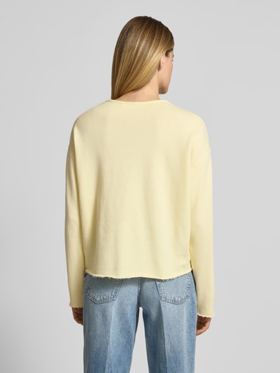 Frauenmodel trägt Sweatshirt mit Brusttasche von Rich & Royal aus reiner Bio-Baumwolle in Pastellgelb, ausgefranster Saum, Ganzkörperansicht Rückansicht.