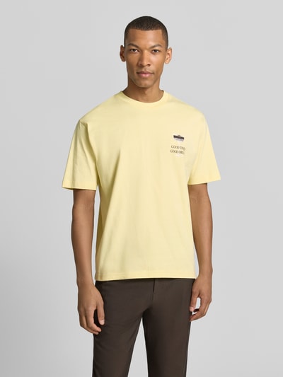 Männermodel trägt T-Shirt mit rückseitigem Motiv-Print von MCNEAL in Pastellgelb, Bio-Baumwolle, gerader Schnitt, Nahaufnahme Oberkörper.