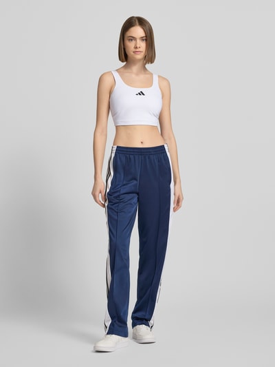 Vrouwenmodel draagt 'BH mit Label-Print' van adidas Sportswear, wit, strakke fit, labelprint, mix van materialen met stretch, volledige vooraanzicht.