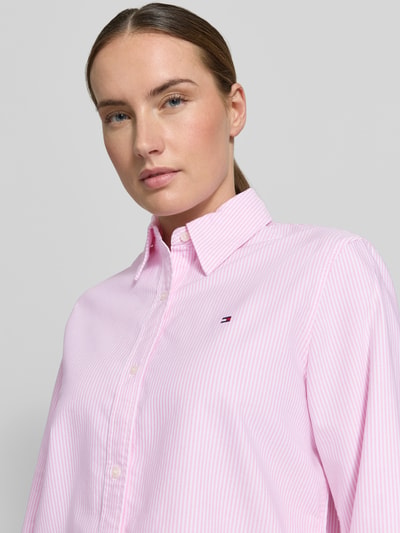 Kobiece modelka ma na sobie Relaxed Fit Hemdbluse aus reiner Baumwolle od Tommy Hilfiger, efekt: jednolity kolor, krój relaxed fit, kołnierzyk koszulowy, detal z logo, pas na plecach, listwa guzikowa, długi rękaw z mankietem, wykończenie zaokrąglone, wykończenie materiału: wzór oxford, materiał: bawełna; zbliżenie na górną część ciała z przodu.