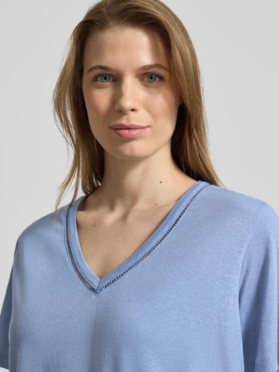 Frauenmodel trägt Relaxed Fit T-Shirt aus Leinen-Mix mit V-Ausschnitt von Scotch & Soda in Blau mit Lochmuster, Nahaufnahme Oberkörper.