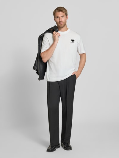Männermodel trägt Relaxed Fit T-Shirt aus reiner Baumwolle von Antony Morato, weiß, Logo-Detail, schwarze Hose, Ganzkörperansicht von vorne. Damen T-Shirt von Antony Morato, reine Baumwolle, Relaxed Fit, Logo-Detail, Rundhalsausschnitt, Rückenlänge bei Größe M: 69 cm.