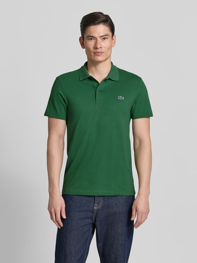 Männermodel trägt Regular Fit Poloshirt aus Baumwoll-Mix von Lacoste in Optik: Unifarben mit Logo-Patch, Polokragen, Kurzarm, Ganzkörperansicht von vorne.