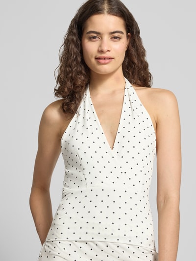 Frauenmodel trägt Slim Fit Top mit Neckholder von Gina Tricot in Weiß mit schwarzen Punkten, V-Ausschnitt, Elastischer-Material-Mix, Rückenlänge bei Größe S 58 cm, Nahaufnahme Oberkörper.