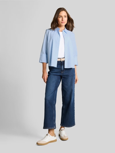 Frauenmodel trägt Regular Fit Hemdbluse aus Lyocell-Baumwoll-Mix von Tom Tailor, hellblau mit Streifen-Optik, Popeline, Kimonoärmel, Ganzkörperansicht von vorne.