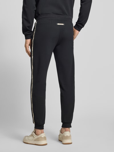 Männermodel trägt schwarze Sweatpants aus Baumwoll-Mix von EA7 Emporio Armani mit Eingrifftaschen, elastischem Bund, Ganzkörperansicht Rückansicht.