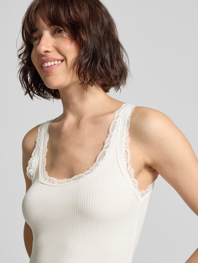 Frauenmodel trägt Slim Fit Tank Top aus Bio-Baumwoll-Mix Modell 'NANA' von Vero Moda, Optik: Unifarben, Spitzenbesatz, U-Ausschnitt, breite Träger, Materialverarbeitung: Ripp, Nahaufnahme Oberkörper.
