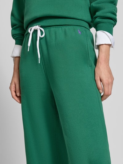 Frauenmodel trägt Wide Leg Sweathose aus Baumwoll-Mix mit Logo-Stitching von Polo Ralph Lauren in kräftigem Grün, glatte Textur, Nahaufnahme Oberkörper, Damen Sweathose von Polo Ralph Lauren