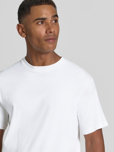 Mężczyznę model nosi biały t-shirt z wyraźną strukturą, produkt Regular Fit T-Shirt aus Baumwoll-Mix Modell 'SPENCER' von Selected Homme, męski t-shirt, zbliżenie na górną część ciała