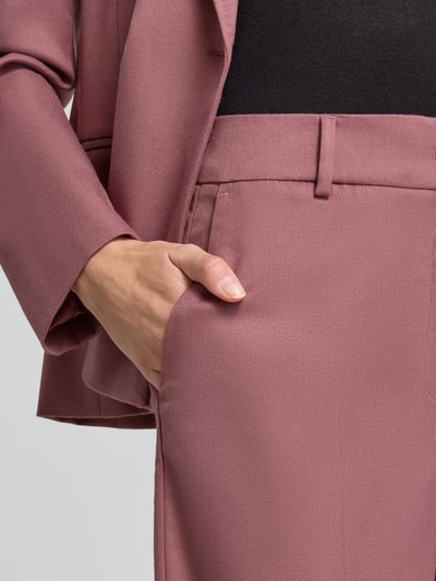 Kobiece modelka nosi spodnie Wide Fit Hose mit Viskose-Anteil von Christian Berg Woman Selection w kolorze pudrowego różu, elastyczna mieszanka materiałów z dodatkiem wiskozy, z kantami i zapięciem na haftkę i zamek błyskawiczny, kontekst: Szerokość w rozmiarze 36: 46 cm, Długość wewnętrzna nogawki w rozmiarze 36: 85 cm, zbliżenie na biodra i kieszeń.