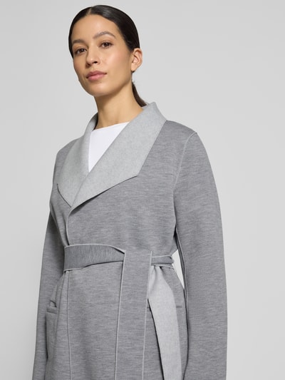 Kobiece modelka nosi Relaxed Fit Mantel mit Viskose-Anteil Modell 'Juice' od Vila, szary kolor, pasek, kieszenie, detal szalowego kołnierza, materiał mieszany, widok na górną część ciała z przodu.