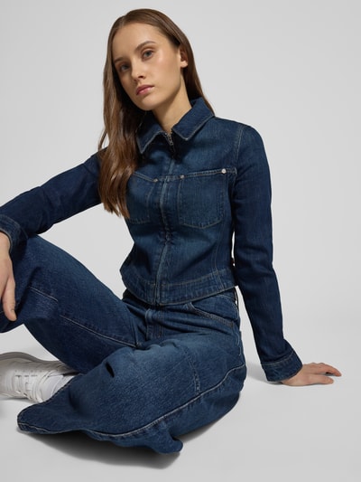 Modelka kobieca ma na sobie Jeansjacke mit Reißverschluss und Label-Detail od Levi's®, granatowy bawełniano-elastanowy krój slim fit, klasyczny kołnierz, widoczne detale label, Szerokość w rozmiarze S: 45 cm, długość tyłu: 43 cm, Szerokość ramion w rozmiarze S: 38 cm, długość rękawa w rozmiarze S: 64 cm, powierzchnia gładka, przód zbliżenie na górną część ciała