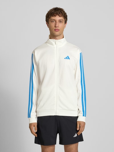 Männermodel trägt Regular Fit Trainingsjacke mit Stehkragen von adidas Sportswear, Optik: Unifarben, Logo-Print, Kontraststreifen, Reißverschluss, Ärmelform: Langarm, Ärmelabschluss: Gerippt, Rumpfabschluss: Gerippt, seitliche Eingrifftaschen, Ganzkörperansicht von vorne.