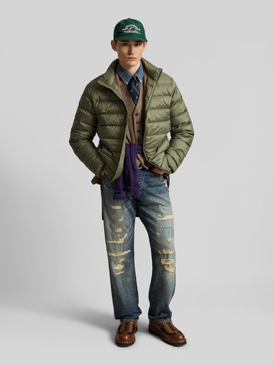 Męski model nosi kurtkę pikowaną Regular Fit Steppjacke mit Logo-Stitching od Polo Ralph Lauren, jednokolorowa, krój regular fit, zamek błyskawiczny, wyhaftowane logo, długi rękaw, wpuszczane kieszenie, stójka, widok całej sylwetki z przodu.