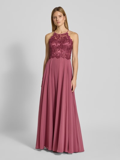 Modelka kobieca ma na sobie 'Abendkleid mit Spitze und Cut Out' od V.M., długi, różowy, zwiewny szyfon, koronka, A-linia, widok z przodu na całe ciało, długość tyłu w rozmiarze 36: 143 cm, szerokość w rozmiarze 36: 35 cm.