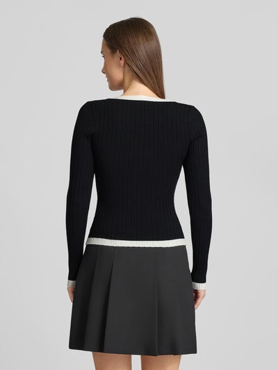 Frauenmodel trägt Slim Fit Longsleeve aus Viskose-Mix Modell 'Laurel' von Guess, Strick-Optik, Zierknöpfe, Ganzkörperansicht Rückansicht.