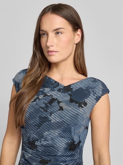 Kobiece modelka nosi Slim Fit Kleid mit Kappärmeln od Swing, elastyczna mieszanka materiałów, asymetryczny dekolt, marszczenia, krótkie rękawy, odcień granatu z czarnym wzorem, zbliżenie na górną część ciała.