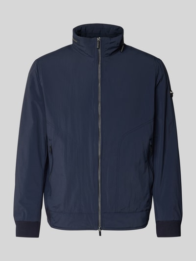 Produktfoto, Regular Fit Jacke mit Stehkragen von bugatti, granatowy kolor, prosta forma, tekstura materiału technicznego, krój regular fit, dwukierunkowy zamek, elastyczne mankiety, kieszenie na zamek, detal z logo, składana kaptur, długość tyłu w rozmiarze 50: 65 cm, szerokość ramion w rozmiarze 50: 47 cm, szerokość klatki piersiowej w rozmiarze 50: 53 cm, długość rękawa w rozmiarze 50: 63 cm.