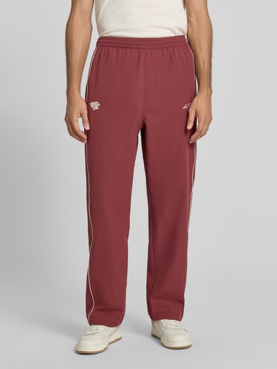 Männermodel trägt Trackpants mit Logo-Stitching Modell 'Seersucker' von Les Deux, strukturierte Oberfläche, Kontraststreifen, Ganzkörperansicht von vorne.