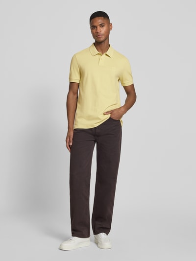 Männermodel trägt Regular Fit Poloshirt aus Baumwoll-Mix Modell 'PASSENGER' von BOSS Orange in Hellgelb, Piqué-Struktur, unifarben, Ganzkörperansicht von vorne.