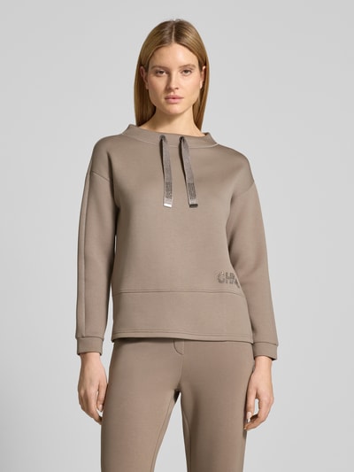 Frauenmodel trägt Loose Fit Sweatshirt aus Viskose-Mix mit Stehkragen von Betty Barclay, taupefarben, elastische Abschlüsse, Ziersteine, Ganzkörperansicht von vorne.