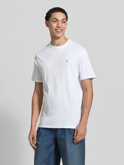 Männermodel trägt T-Shirt mit Label-Patch Modell 'BADGE' im 2er-Pack von Calvin Klein Jeans, reine Baumwolle, weiß, Ganzkörperansicht von vorne.