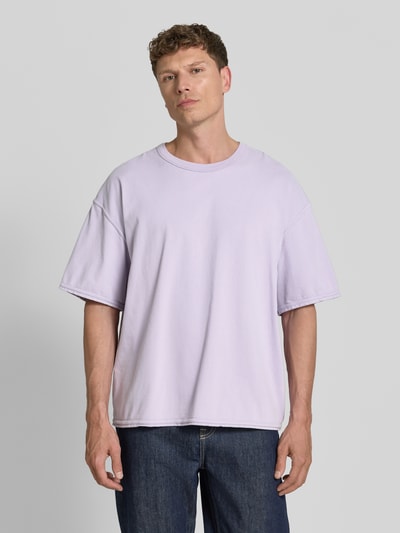 Männermodel trägt Herren T-Shirt mit überschnittenen Schultern Modell 'FAZY' von American Vintage, Reine Baumwolle, Loose-Fit, Rundhalsausschnitt, dezenter Flieder-Ton, glatte Struktur, Rückenlänge bei Größe M/L: 70 cm, Ganzkörperansicht von vorne.