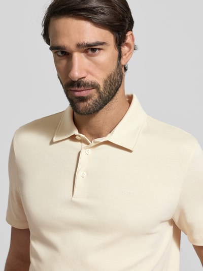 Männermodel trägt Regular Fit Poloshirt aus reiner Baumwolle Modell 'PALOSH' von BOSS, Optik: Unifarben, Label-Print, Nahaufnahme Oberkörper.