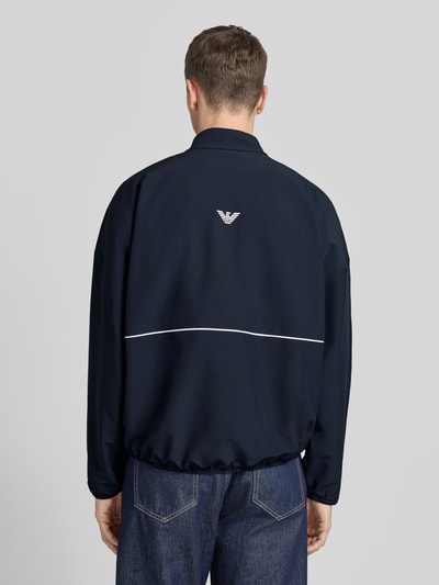 Männermodel trägt dunkelblaue Bomberjacke mit Stehkragen und Logo-Print von EA7 Emporio Armani, elastische Abschlüsse, Rückenansicht, Kontext: Herrenmodell, gerader Schnitt, Zweiwege-Reißverschluss, VENTUS7-Funktionsgewebe, Rückenlänge 71 cm, Schulterbreite 75 cm, Brustweite 66 cm, Ärmellänge 54 cm.