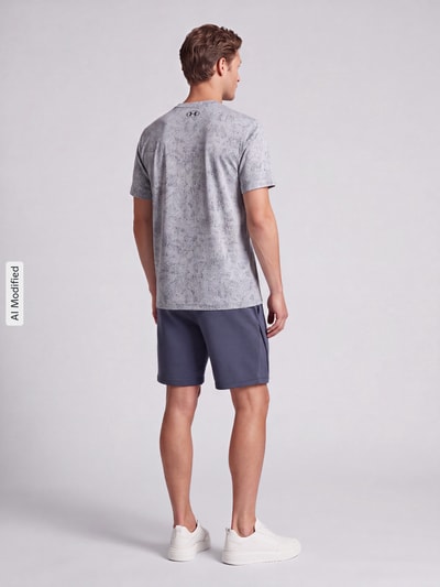 Männermodel trägt Regular Fit T-Shirt mit Strukturmuster Modell 'Pixelate' von Under Armour in Grau, lockere Passform, Ganzkörperansicht Rückansicht, KI-modifiziertes Bild. Herren Sport-T-Shirt von Under Armour.