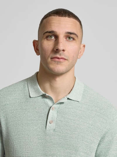 Männermodel trägt Regular Fit Poloshirt mit Strukturmuster Modell 'GEORGE' von Jack & Jones aus Baumwoll-Mix mit Knopfleiste, Nahaufnahme Oberkörper.